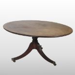 A George III mahogany breakfast table, with a hinged oval top, on a turned column and splayed base,