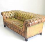 A mid 20th century leather chesterfield sofa, with a buttoned back and seat, on bun feet,