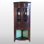 An Edwardian mahogany and inlaid bow front standing corner cabinet, with a glazed upper section,