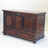 An 18th century oak mule chest, with a hinged lid and panelled front,