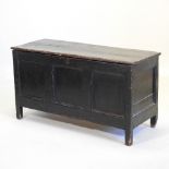 An 18th century stained pine coffer, with a hinged lid and panelled front, on stile feet,
