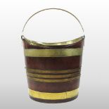A George III mahogany and brass banded bucket, of oval shape, with a swing handle,