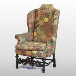 An early 20th century floral upholstered armchair, of 17th century style, on carved legs,