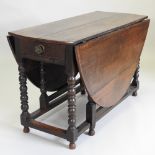 An 18th century oak gateleg dining table, with a hinged oval top, on bobbin turned legs,