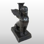A patinated bronze figural candlestick, modelled as an Egyptian winged sphinx,