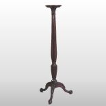 A George III style mahogany torchere, with a fluted baluster column, on a tripod base,