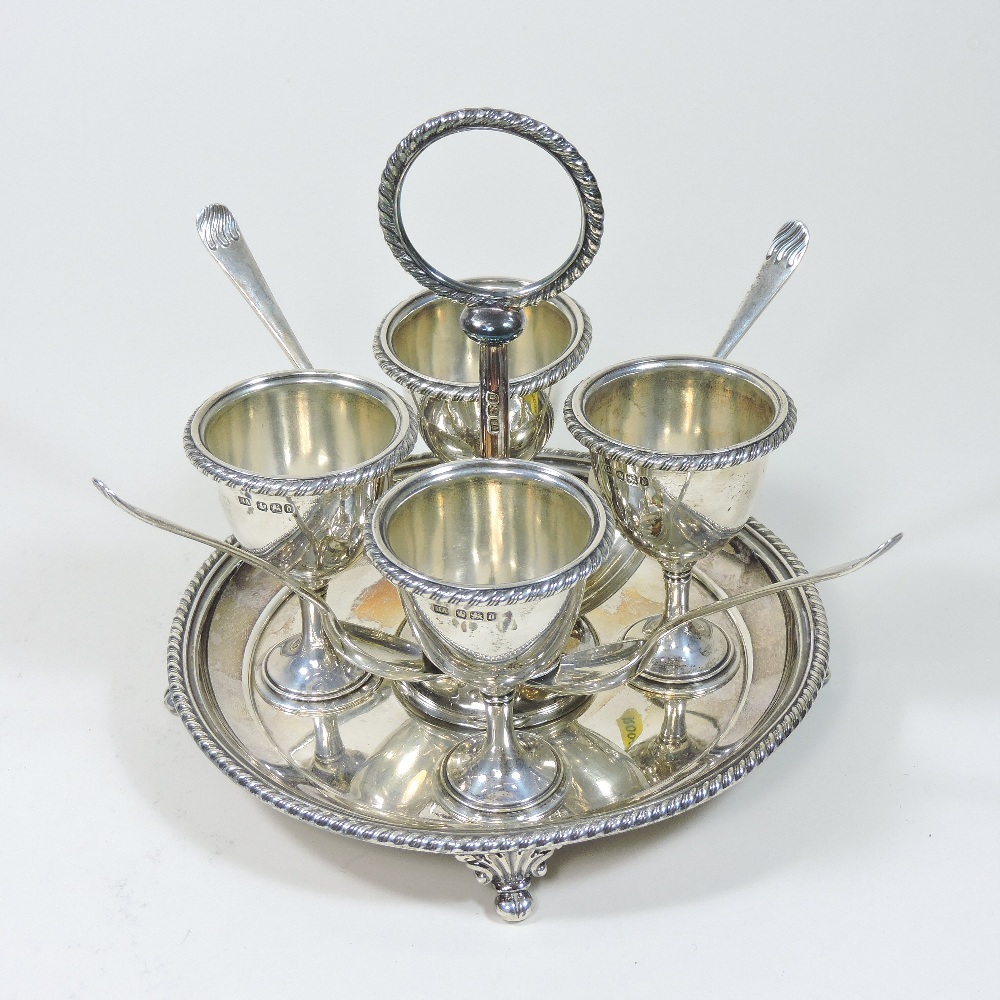 A Victorian silver egg cruet, of circular shape, fitted with four egg cups and four silver spoons,