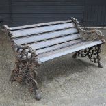 An ornate black painted cast iron garden bench, with a slatted wooden seat,