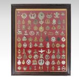 A collection of military cap badges, in an early 20th century glazed oak display frame,