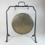 A brass dinner gong, on a wrought iron stand,