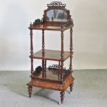 A Victorian walnut three tier whatnot, with fret carved decoration and a mirrored back,