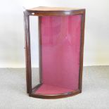 An early 20th century shop display cabinet, with a curved glass front and door behind,