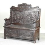 A 19th century heavily carved dark oak Green Man box settle, with a rising seat,