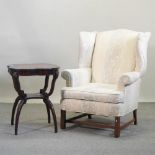 A Georgian style cream upholstered wing armchair, together with a leather top occasional table,