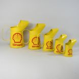 A set of five modern metal Shell graduated oil cans,