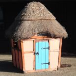 A painted wooden and Norfolk reed thatched children's playhouse, 180cm wide x 210cm high.