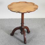 A Victorian Gothic carved light oak occasional table, with a shaped circular top, on a tripod base,