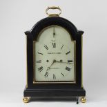 A 19th century ebonised bracket clock, with pierced grille sides, surmounted by a gilt metal handle,