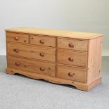 A modern pine chest of long drawers,