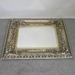 An ornate silver painted wall mirror,