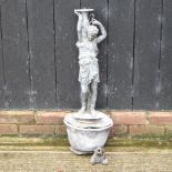 A cast iron garden fountain, of a boy holding an urn, standing on a lily pad, on a on a lead bowl,