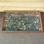 A display case, containing miniature cap pistols and guns,