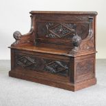 A 19th century carved oak box settle, with a rising seat,