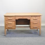 A 1930's light oak kneehole desk,