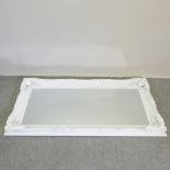 A large ornate white framed wall mirror,