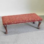 A Victorian style red upholstered footstool, on cabriole legs,