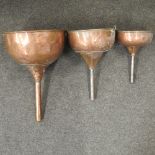 A set of three 19th century graduated copper funnels,