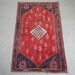 A large Persian carpet, with a central medallion, and geometric design, on a red ground,