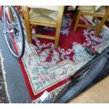 A Chinese wool rug with floral design in reds, creams and greens.