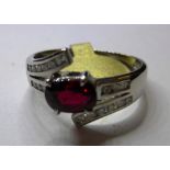 An 18ct white gold, ruby and diamond cross over ring (size L)