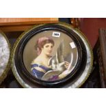 A 19th century Continental porcelain circular wall plaque, painted with a girl in blue dress holding