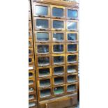 A vintage oak haberdasher's or habersdashery cabinet with glassfront drawers.