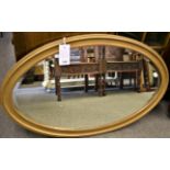 An oval gilt wall mirror with bevelled glass (45cm x 81.5cm)