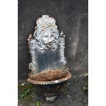 A cast iron fountain plate with decorated lions head.