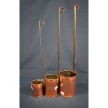 A set of three graduated copper measuring cups with long handles.