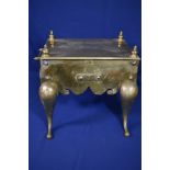 An early 19th century brass footman the rectangular top with turned finials, over shaped sides