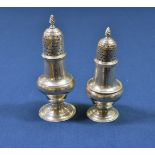 Two George III silver baluster pepper casters both of similar design, having dot pierced covers