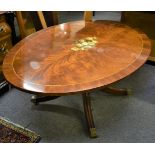 A reproduction oval table with central floral decoration inlaid stringing and brass casters,