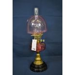 An antique cranberry coloured glass and brass oil lamp.