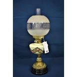 An antique brass oil lamp with etched glass globe and floral decoration.