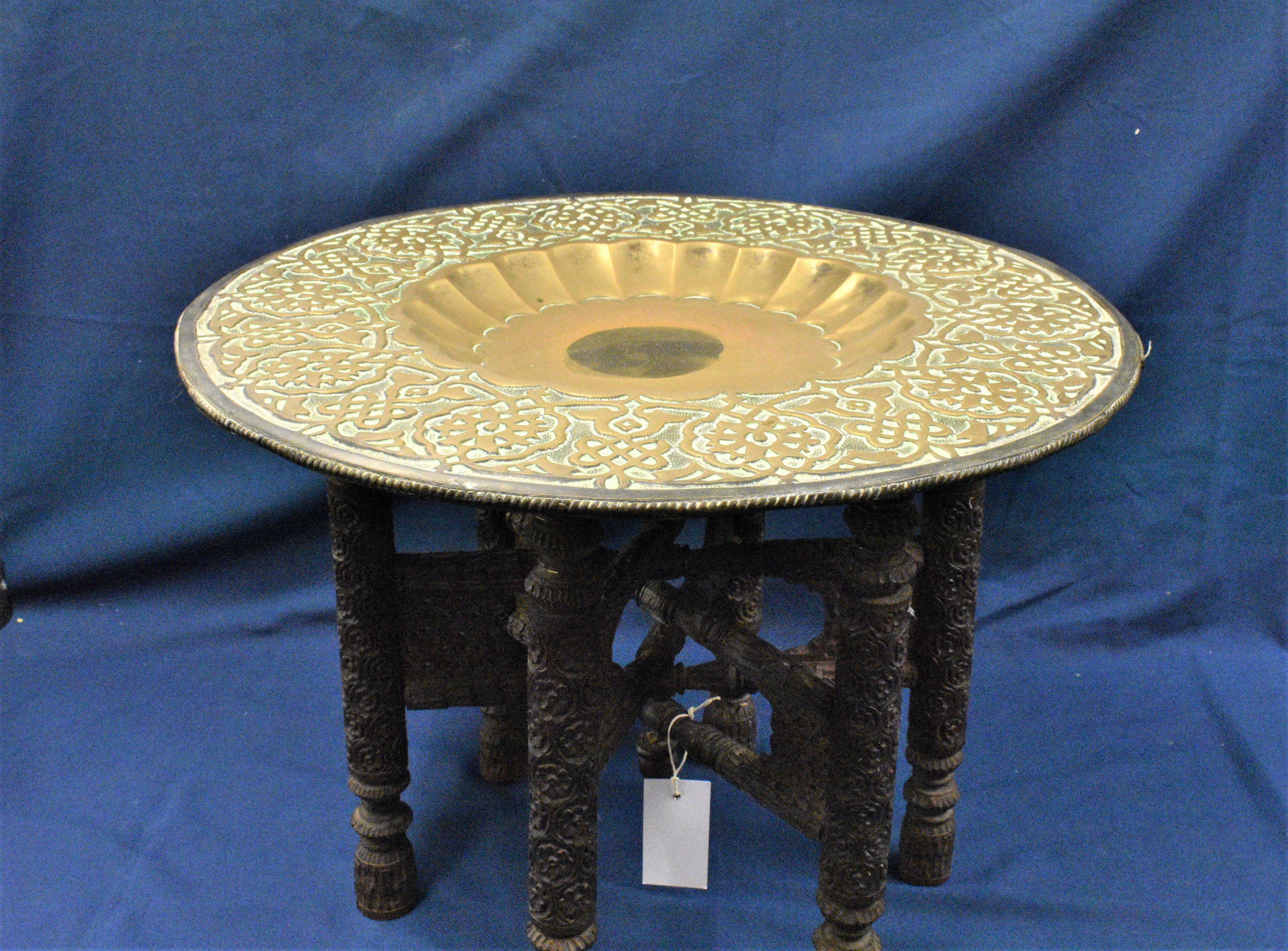 An antique Eastern brass tiffin table with dished top with calligraphy around the border, on a