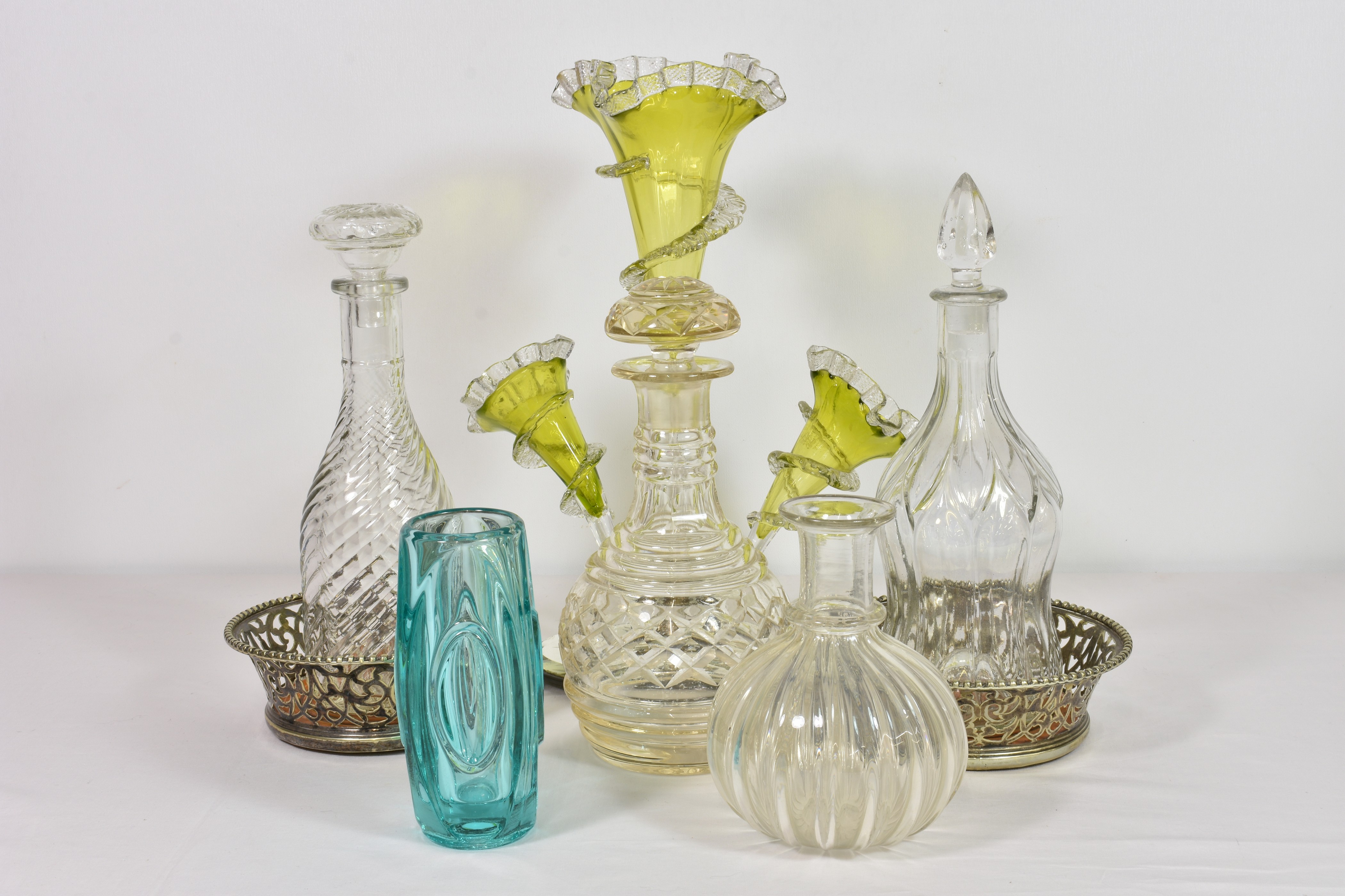 An antique green and clear glass epergne the three flutes with wavy rims and clear glass spiral