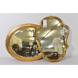An antique oval giltwood mirror with bevelled plate, together with a scroll framed gilt wall mirror.