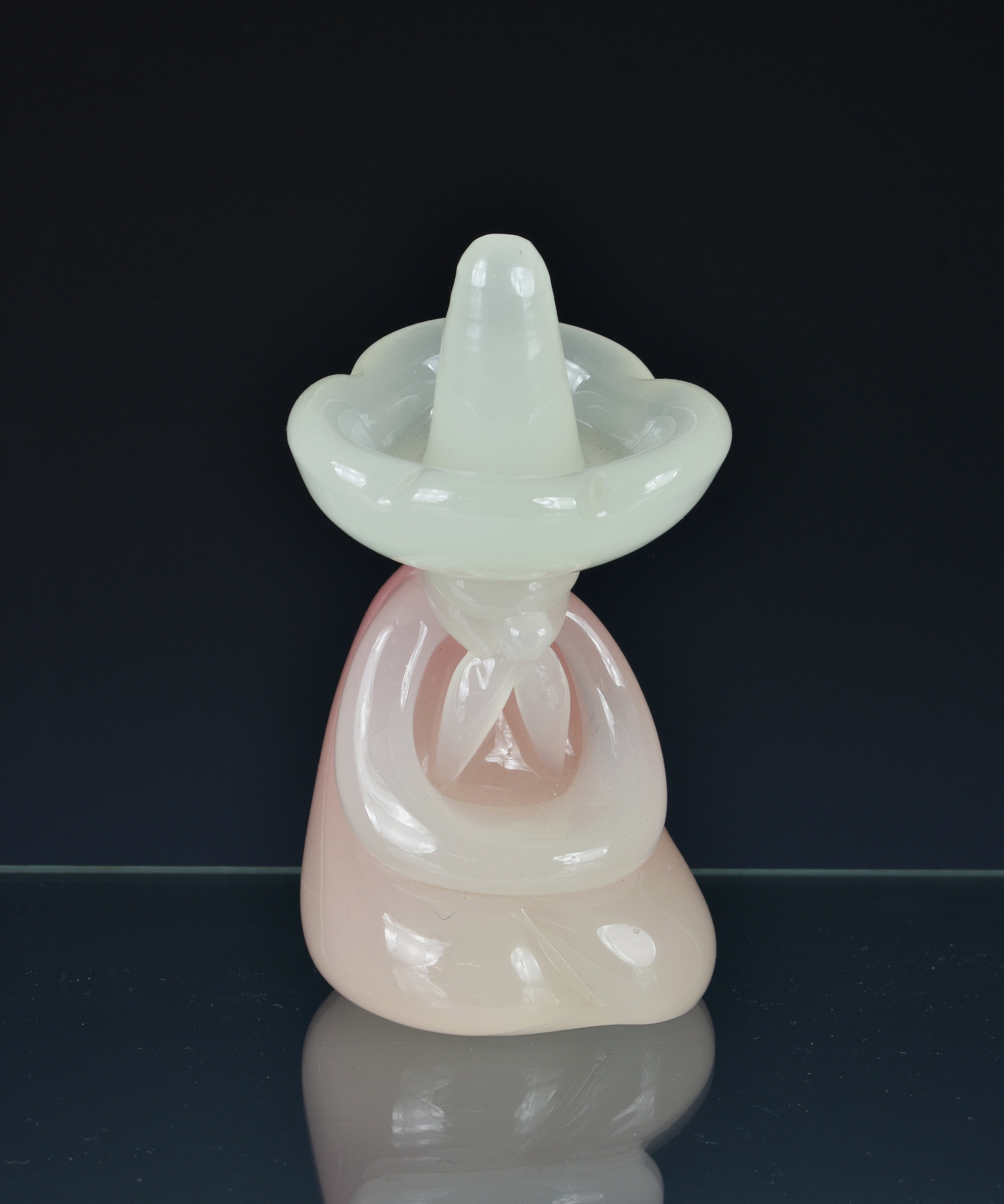 An Archimede Seguso Murano glass Mexican, in pink and white milk glass, seated wearing a sombrero,