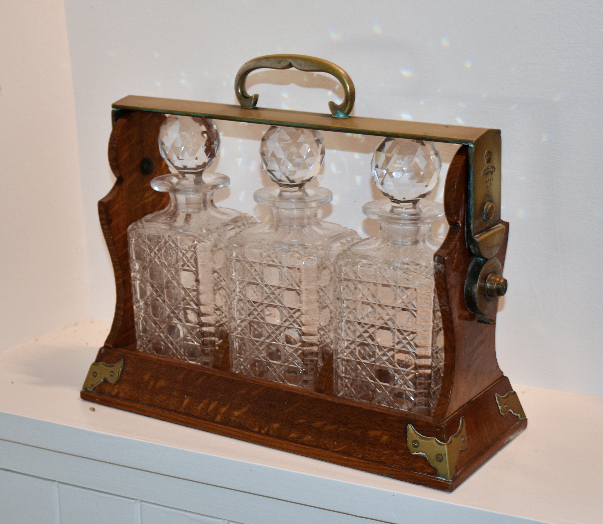 A Victorian brass bound oak Betjeman's Patent three bottle Tantalus, with diamond and hobnail cut