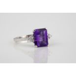 An 18ct white gold, amethyst and diamond ring the emerald cut amethyst over shoulders set with trios
